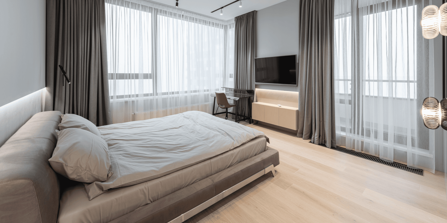 Modern bedroom with a bed, TV, and large windows.