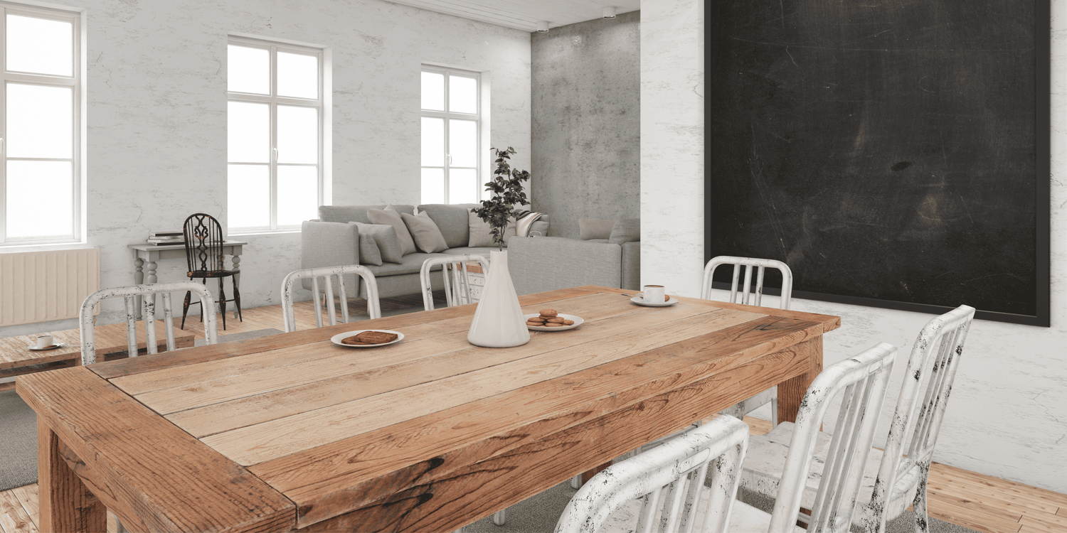Dining room with wooden table and chairs in a bright room with large windows and a blackboard wall.