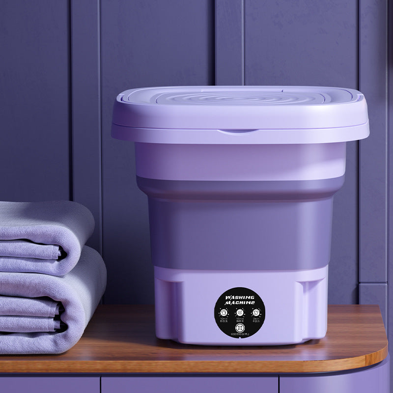 Purple folding washing machine on a wooden surface with purple walls in the background